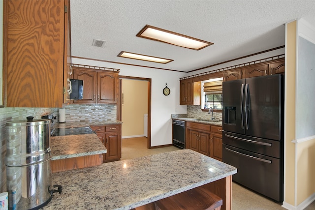 kitchen with sink, tasteful backsplash, black appliances, light stone countertops, and kitchen peninsula