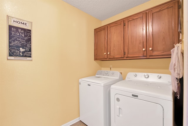 laundry area featuring washer and dryer, cabinets, and a textured ceiling