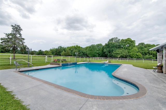 view of swimming pool with a yard, a rural view, and a patio area