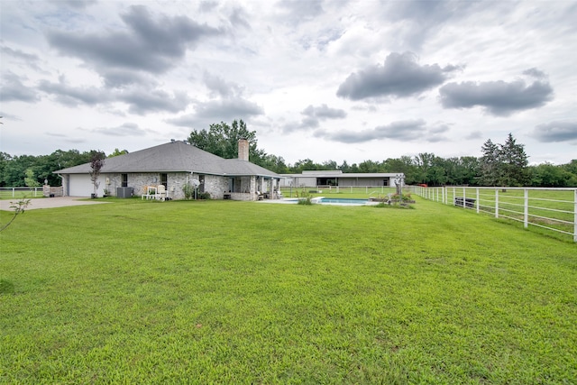 view of yard with a garage and a fenced in pool