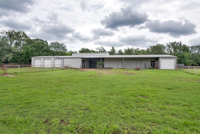 rear view of property featuring an outbuilding, a garage, and a yard