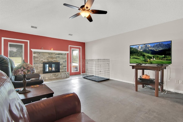 living room featuring ceiling fan, a fireplace, concrete floors, and a textured ceiling