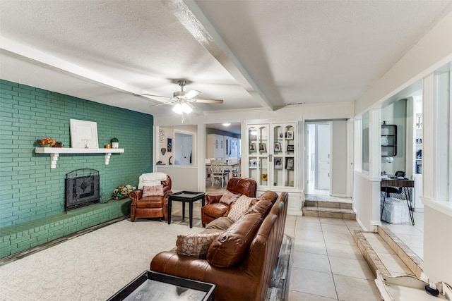 tiled living room featuring a fireplace, beam ceiling, a textured ceiling, and ceiling fan