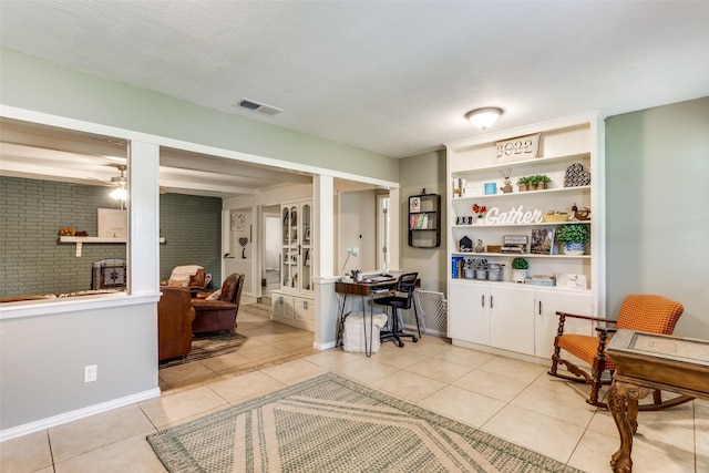 living area featuring built in shelves, ceiling fan, light tile patterned floors, and a textured ceiling