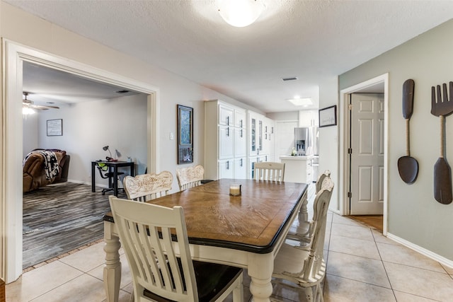 tiled dining space featuring ceiling fan and a textured ceiling