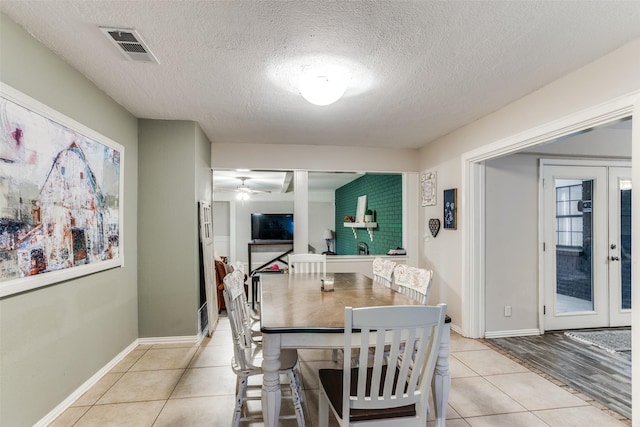 tiled dining room featuring french doors, a textured ceiling, and ceiling fan