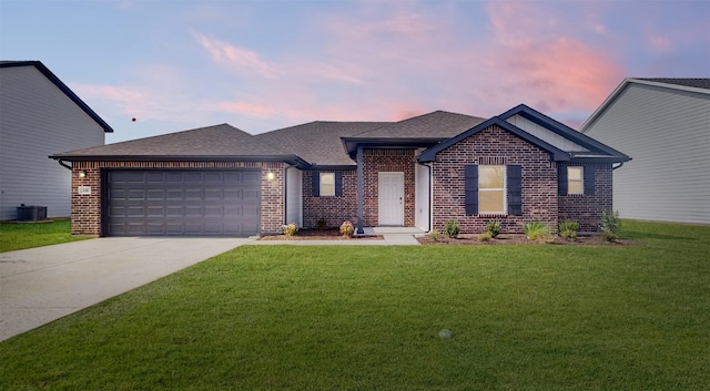 view of front of home featuring a garage, a yard, and central AC unit