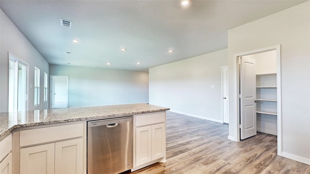 kitchen featuring light stone countertops, light wood-type flooring, white cabinets, and stainless steel dishwasher