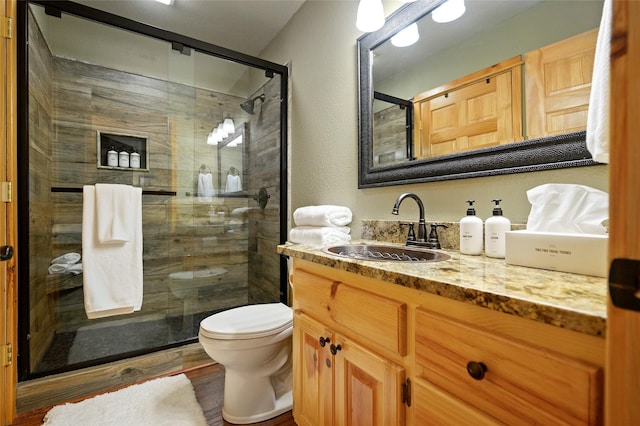 bathroom with wood-type flooring, vanity, toilet, and walk in shower