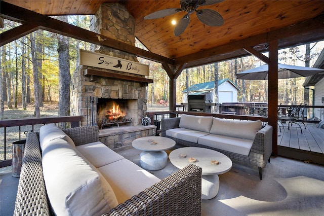 view of patio / terrace with an outdoor living space with a fireplace, ceiling fan, and a deck