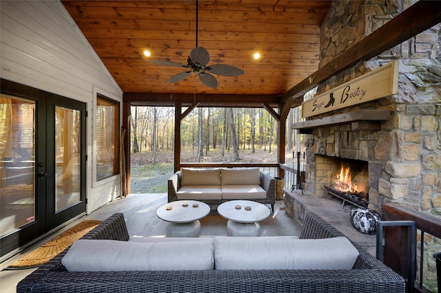 sunroom featuring an outdoor stone fireplace, a healthy amount of sunlight, ceiling fan, and vaulted ceiling