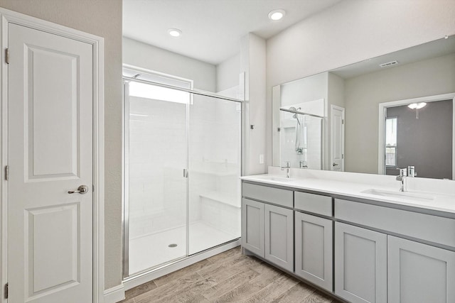 bathroom with walk in shower, vanity, and hardwood / wood-style floors