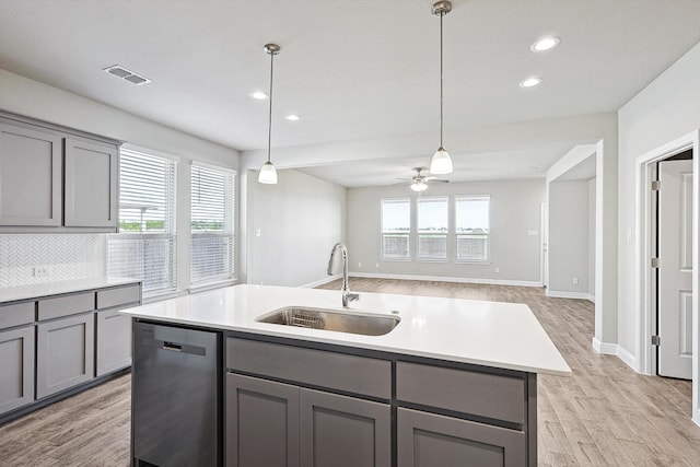 kitchen featuring stainless steel dishwasher, sink, plenty of natural light, and an island with sink