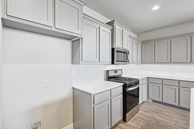 kitchen featuring backsplash, appliances with stainless steel finishes, gray cabinetry, and light hardwood / wood-style floors