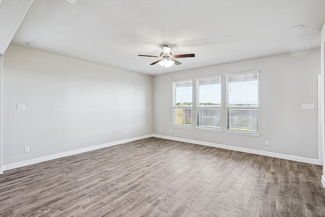 empty room with ceiling fan, wood-type flooring, and a textured ceiling