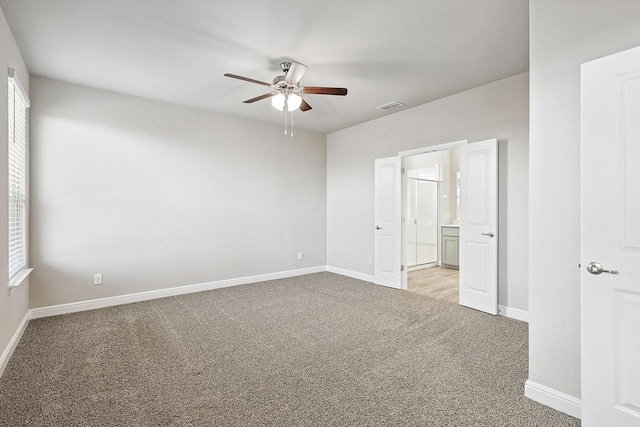 carpeted spare room featuring plenty of natural light and ceiling fan