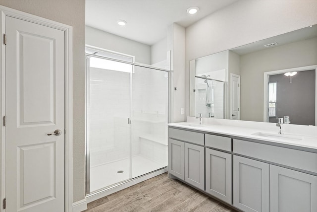 bathroom featuring vanity, a shower with shower door, wood-type flooring, and a wealth of natural light