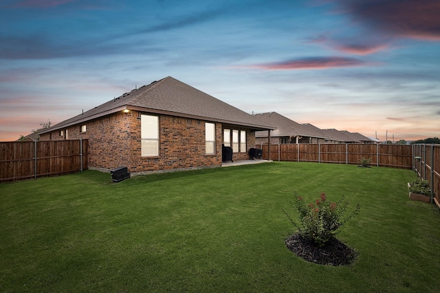 back house at dusk with a lawn