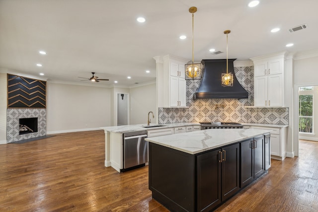 kitchen with kitchen peninsula, custom exhaust hood, stainless steel appliances, sink, and pendant lighting