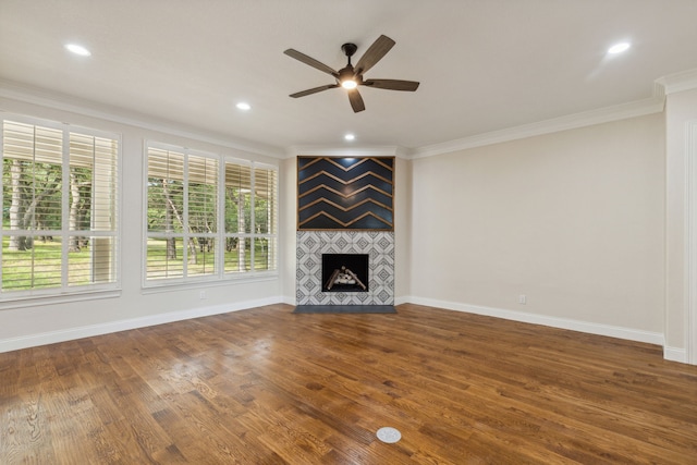 unfurnished living room with a tile fireplace, ornamental molding, hardwood / wood-style flooring, and a healthy amount of sunlight