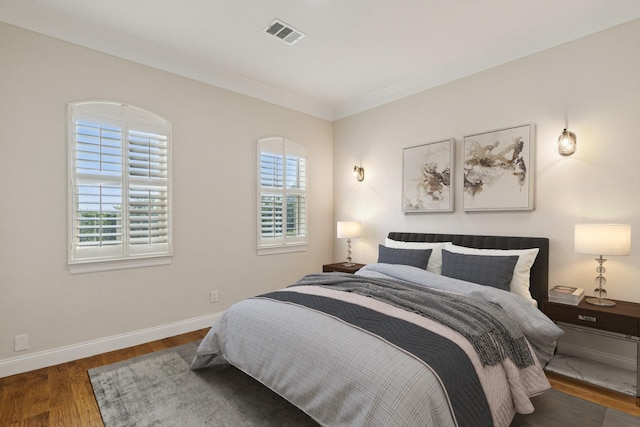 bedroom featuring multiple windows, crown molding, and dark wood-type flooring