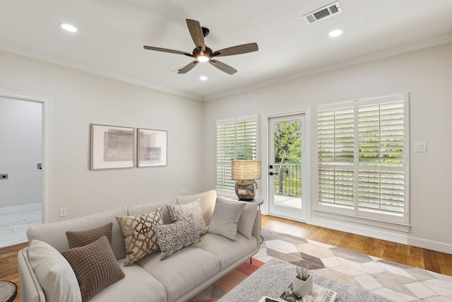 living room with light hardwood / wood-style floors, ceiling fan, and ornamental molding