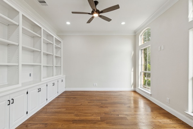 empty room with ornamental molding, dark hardwood / wood-style floors, ceiling fan, and a healthy amount of sunlight