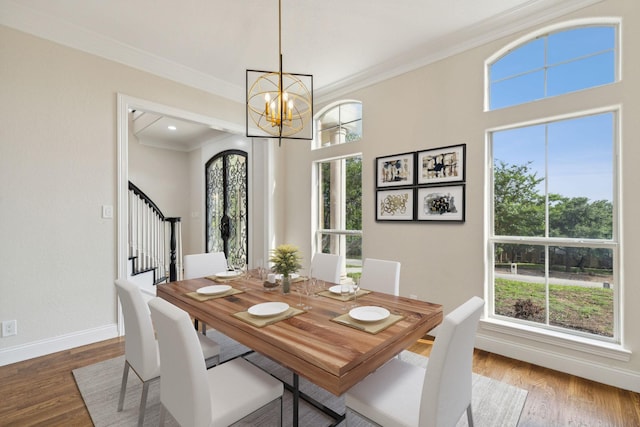 dining room with hardwood / wood-style floors, ornamental molding, and a notable chandelier