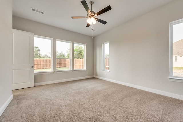 unfurnished room with ceiling fan, a wealth of natural light, and light colored carpet