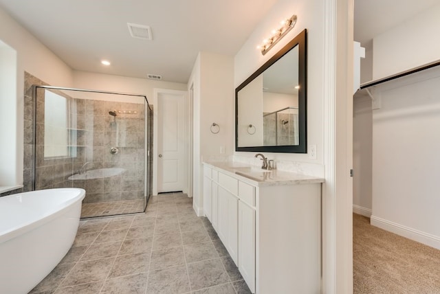 bathroom featuring visible vents, a shower stall, vanity, a freestanding tub, and baseboards