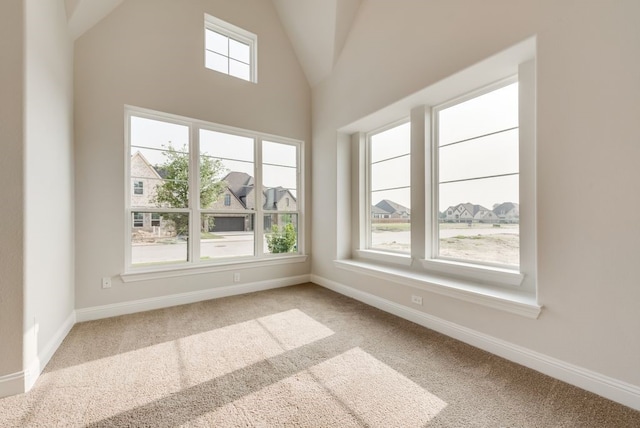 carpeted spare room featuring high vaulted ceiling