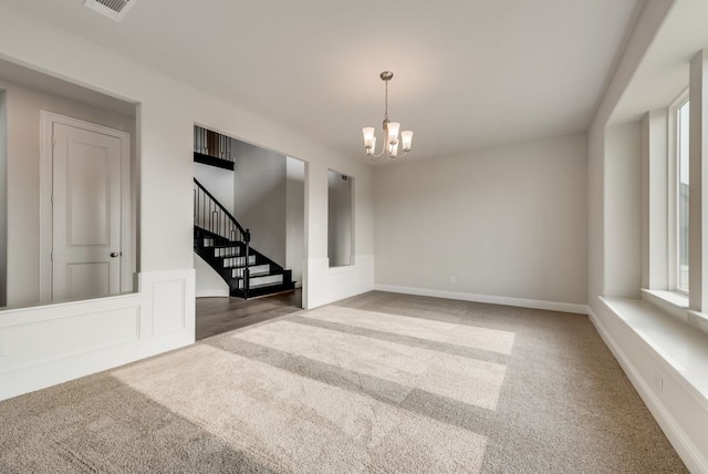 carpeted spare room with a notable chandelier