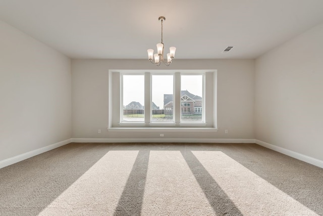 carpeted empty room featuring a notable chandelier