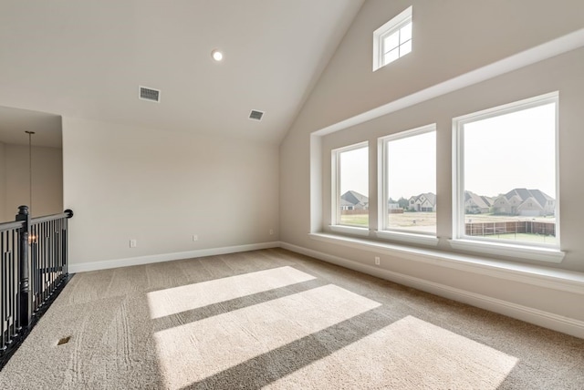 spare room featuring light carpet and high vaulted ceiling