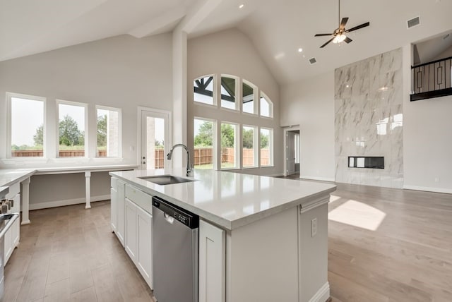 kitchen featuring an island with sink, a premium fireplace, dishwasher, white cabinets, and sink