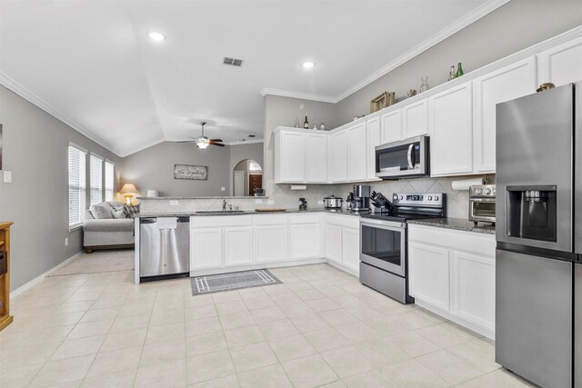 kitchen featuring lofted ceiling, sink, white cabinetry, stainless steel appliances, and backsplash