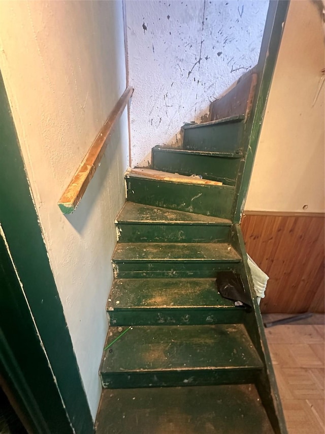 staircase with wood walls and parquet floors