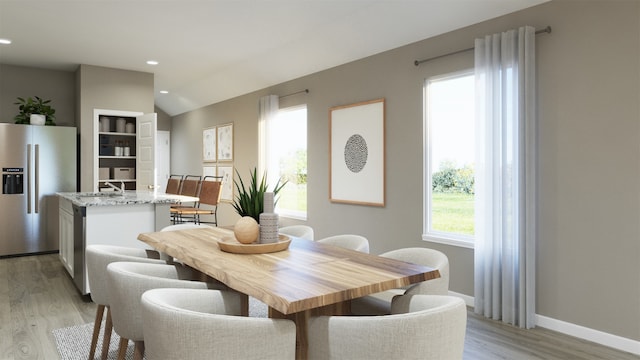 dining area with lofted ceiling, sink, and light hardwood / wood-style flooring