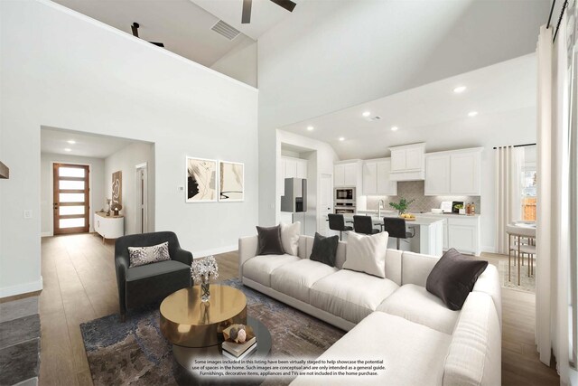 living room with light wood-type flooring, high vaulted ceiling, and sink