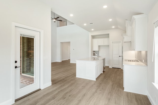 kitchen with light hardwood / wood-style flooring, a center island with sink, and tasteful backsplash