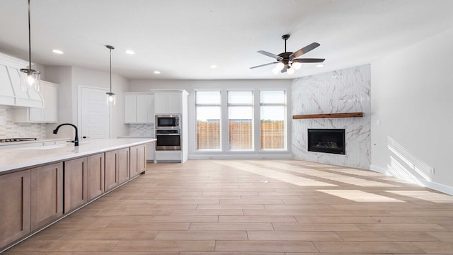 kitchen with appliances with stainless steel finishes, white cabinets, light wood-type flooring, and pendant lighting