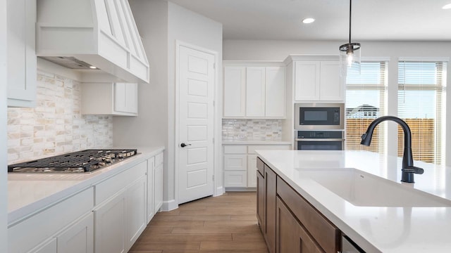 kitchen with appliances with stainless steel finishes, sink, backsplash, hanging light fixtures, and white cabinets