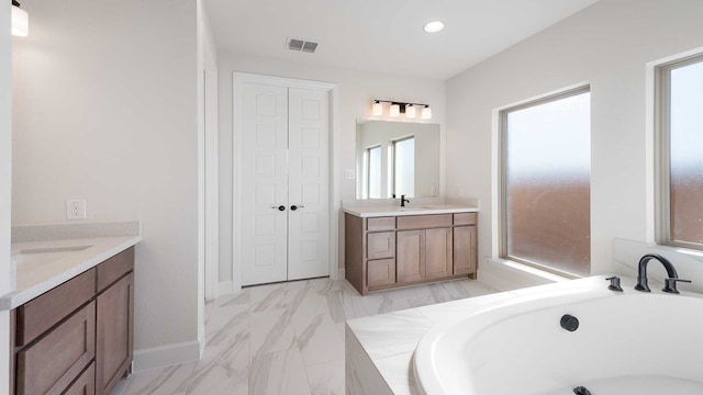 bathroom with a wealth of natural light, vanity, and a tub