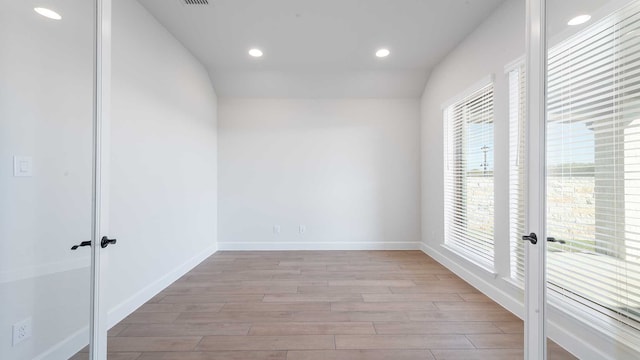 empty room with light hardwood / wood-style floors and vaulted ceiling