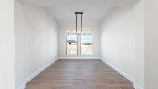 unfurnished dining area with hardwood / wood-style flooring and a chandelier