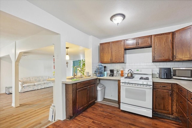 kitchen featuring sink, dark hardwood / wood-style flooring, tasteful backsplash, and white range with gas stovetop