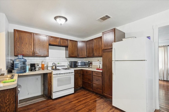 kitchen featuring tasteful backsplash, white appliances, and dark wood-type flooring