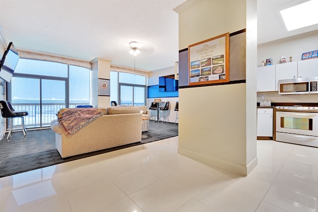 tiled living room featuring a healthy amount of sunlight and floor to ceiling windows