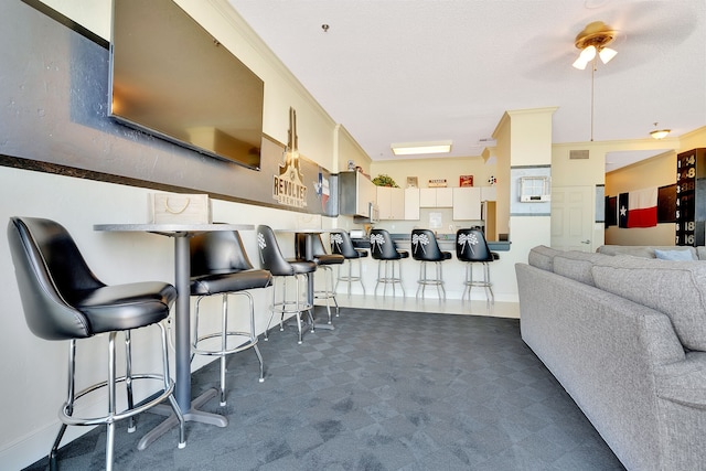 carpeted dining space with bar area and ornamental molding