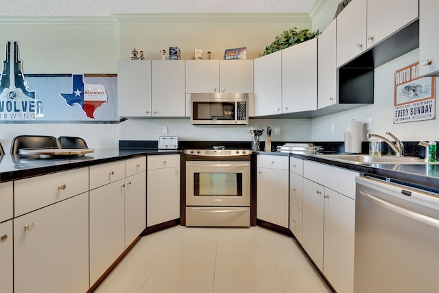 kitchen featuring appliances with stainless steel finishes, white cabinetry, ornamental molding, and light tile flooring